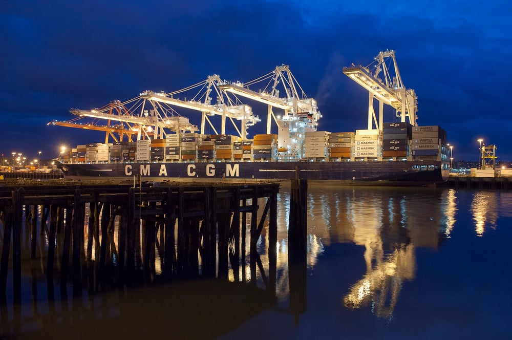 Marine terminal container shipping yard at night with lights turned on.